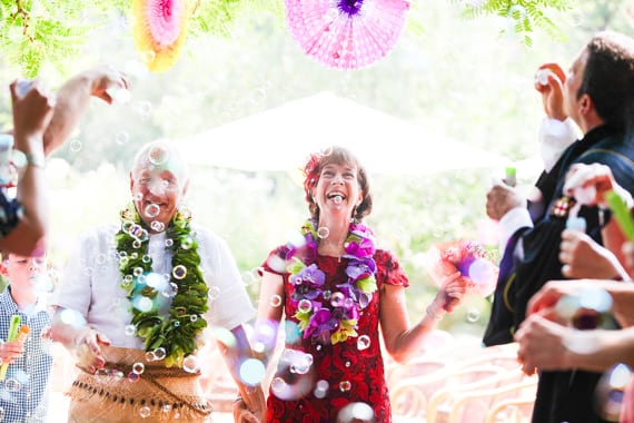 Bubbles shower the newlyweds having a late life marriage ceremony walking down the aisle together.