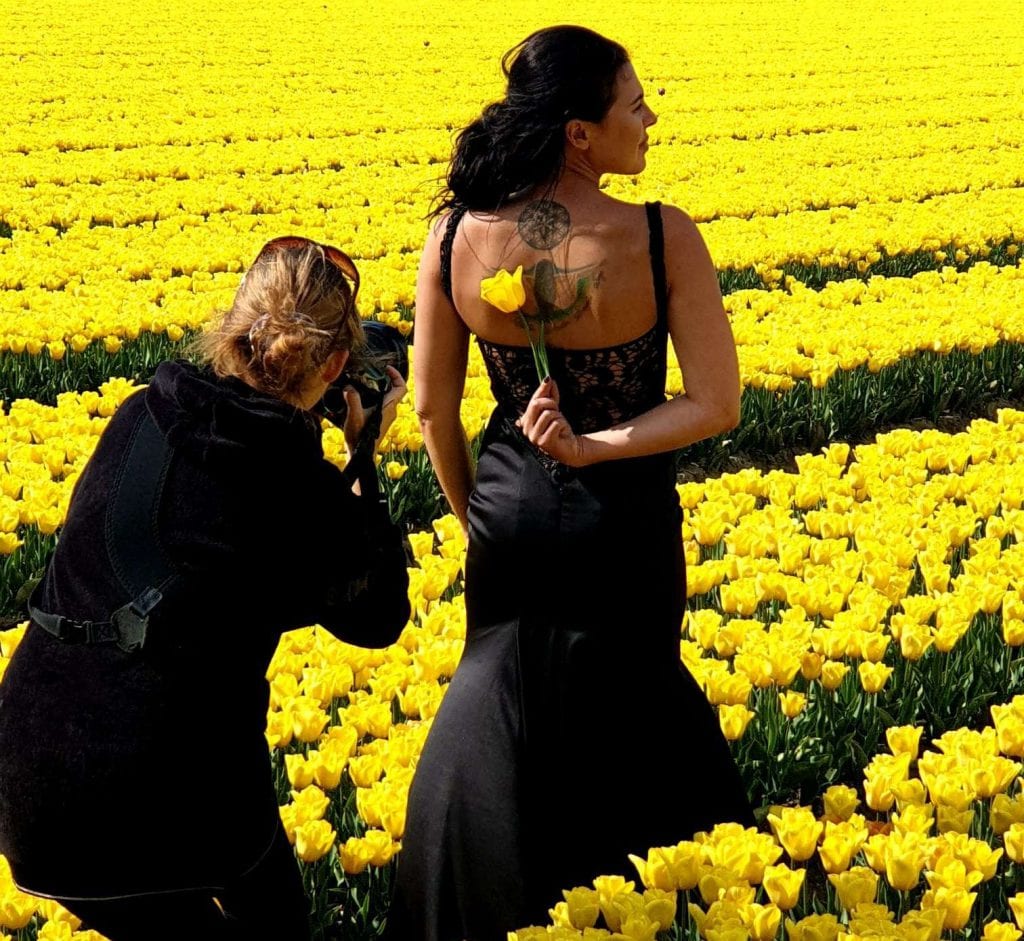  wedding photographer and bride holding tulip in a field