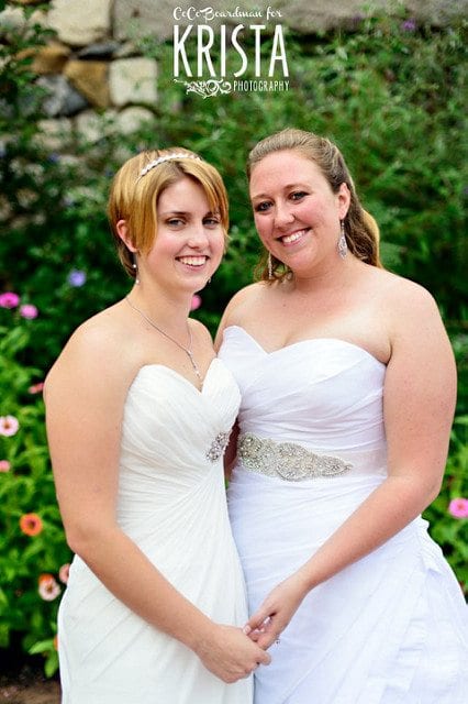 wedding ceremony readings two brides dressed in gowns holding hands