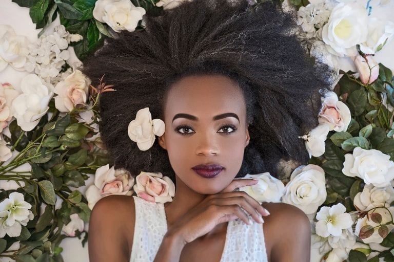 Afro wedding hairstyle bride surrounded by white and pink roses