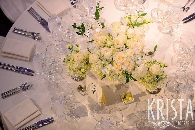 thuis trouwen round table with white flowers, knives, forks and signage