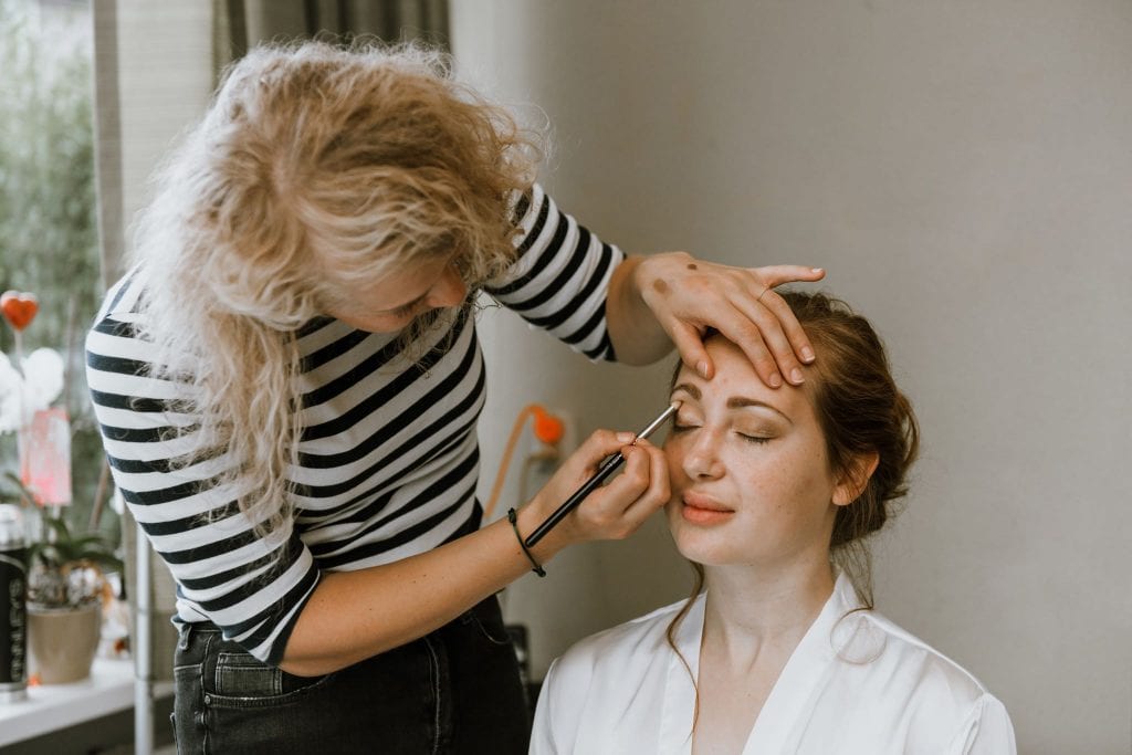 wedding day hair make-up artist applying eyeshadow on bride's eyes