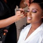 wedding day hair black woman applying eye-shadow on womans face