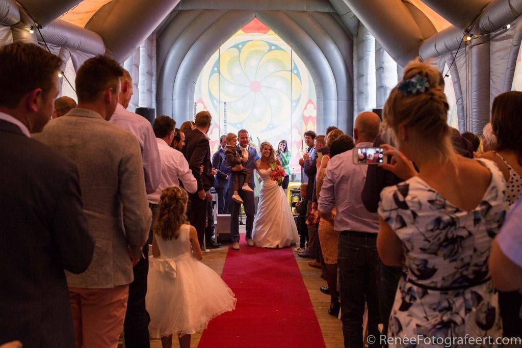 Na de ceremonie verlaat het bruidspaar met kind als eerste de grijze opblaaskerk