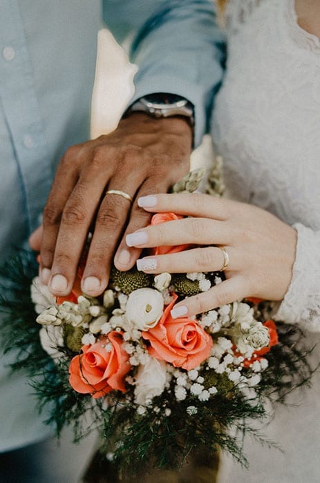 black african man holding a white woman's ringed hand