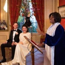 Dutch wedding guide couple holding hands and smiling at lady registrar