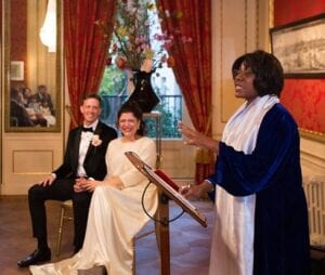 Dutch wedding guide couple holding hands and smiling at lady registrar