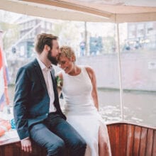 getting married aboard a beautiful boat in amsterdam couple sitting in the back of the boat kissing