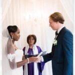 wedding reviews black bride in white laced dressed holding white grooms hand dressed in dark blue tuxedo