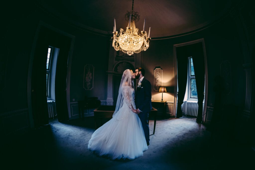 symboli wedding ceremony planning couple kissing under a crystal chandelier