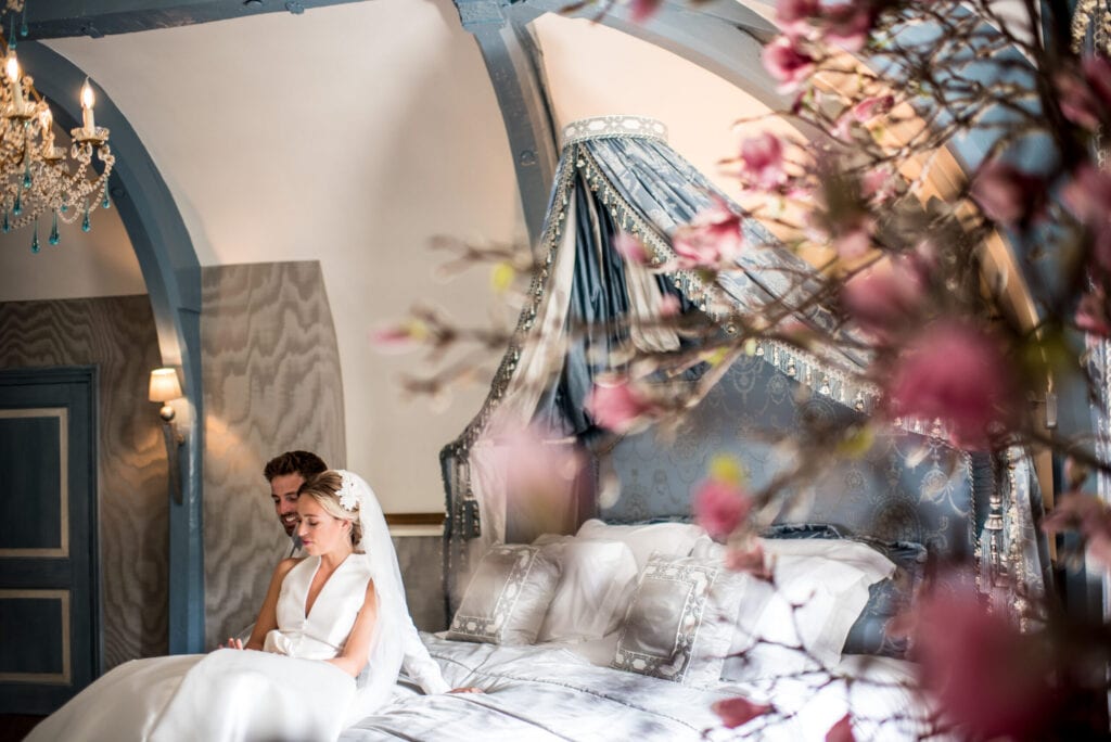hippe bruiloft ideeën superluxe hotel zittend echtpaar op bed in bruidssuite op de eerste huwelijksnacht