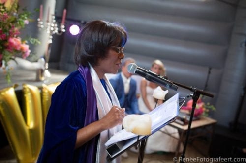Thuis trouwen ceremoniespreker gekleed in donkere blauwe toga met bruidspaar