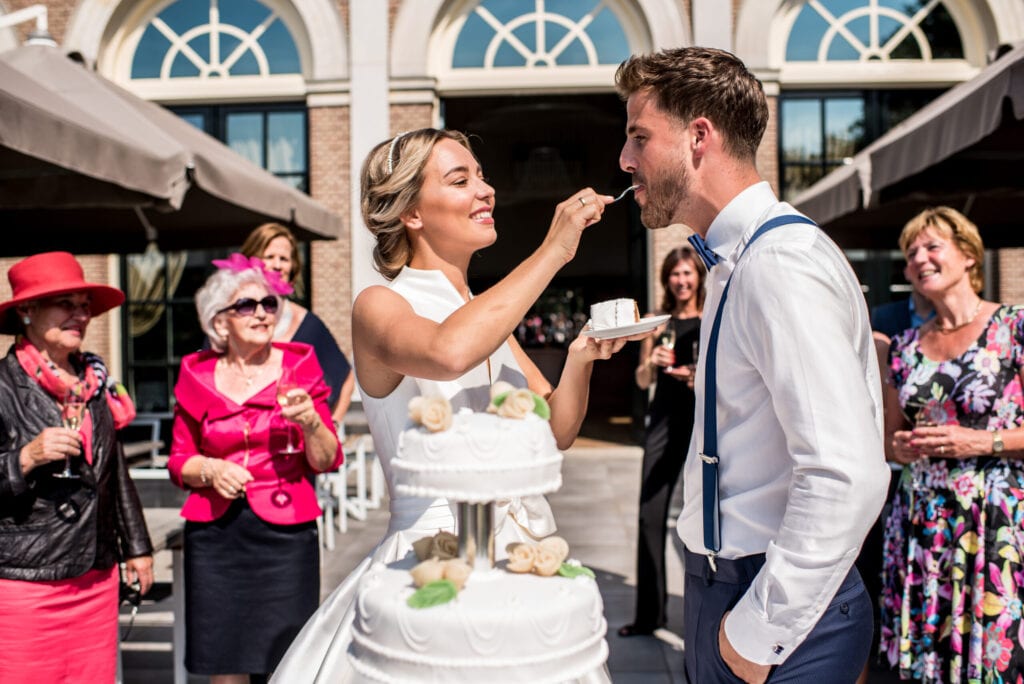 Trouwen in een orangerie bruidstaart gesnijden bruid neemt een stukje en voert dit aan haar man. taart gegeten en bubbels ingeschonken.