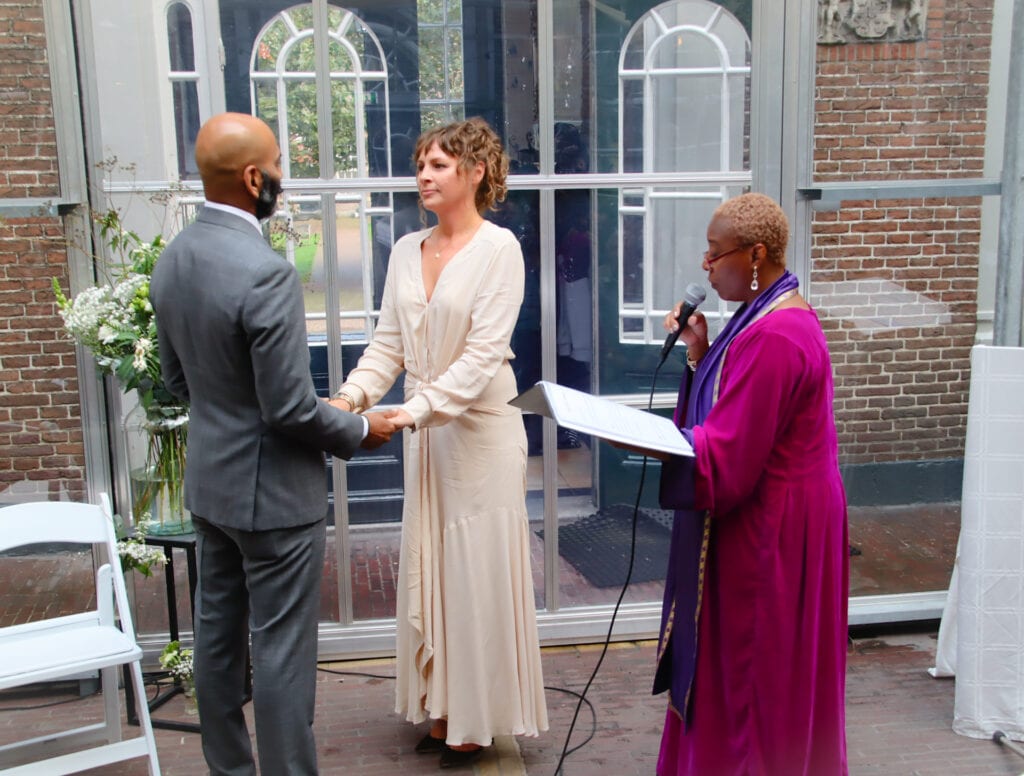 Corona maatregelen voor bruiloften tv-presentatrice en trouwambtenaar met echtpaar van gemengd ras