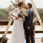 Afro wedding hairstyles black couple bride and groom kissing under arch