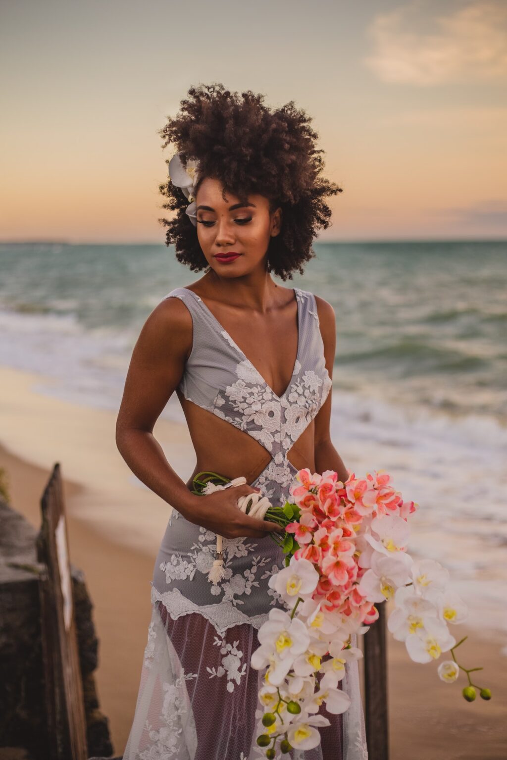 Afro wedding hairstyles stylish black bride with flower bouquet walking near ocean