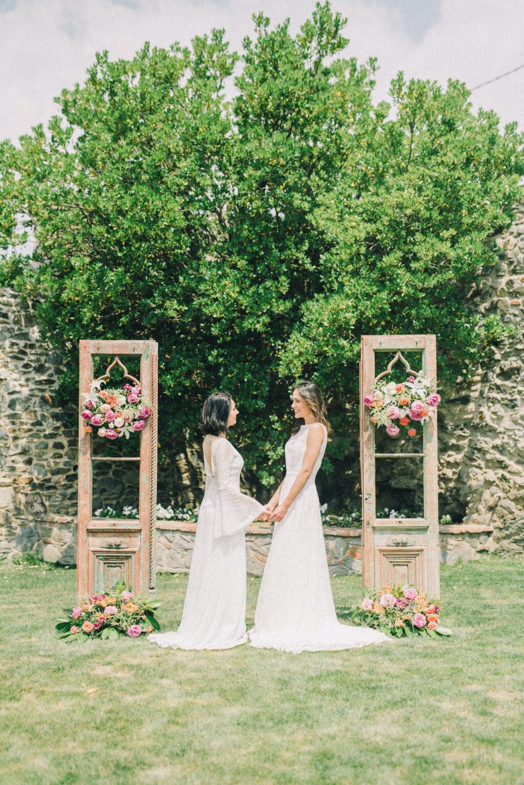 same-sex couple women holding hands and celebrating during an outdoor ceremony wedding in the country.