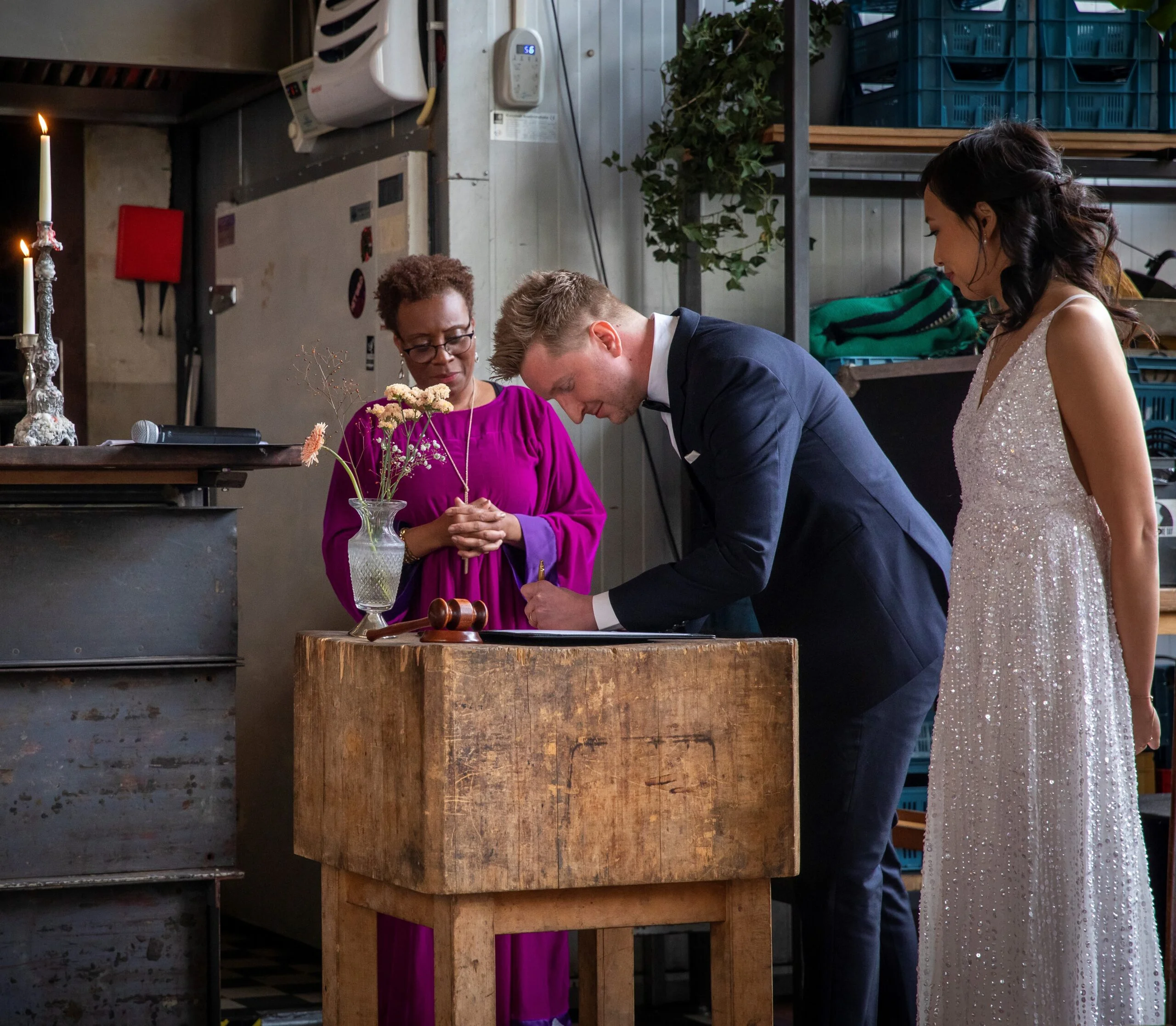 Celebration of love and unity with officiant wearing a purple toga - wedding ceremony rituals to honour a family heirloom, with the celebrant overlooking the signing of the symbolic marriage certificate.