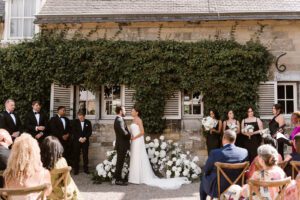 Luxury wedding officiant delivers a speech about the couple's love story as the bride and groom gaze at each other in one of the best Dutch castle wedding venues, Chateau Neercanne.