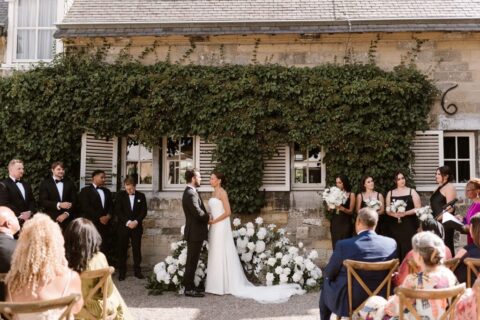 Luxury wedding officiant delivers a speech about the couple's love story as the bride and groom gaze at each other in one of the best Dutch castle wedding venues, Chateau Neercanne.
