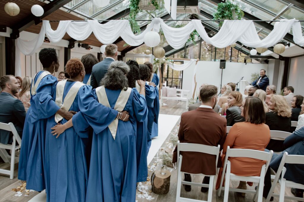 Swingend black gospelkoor: groot gospelkoor bij de bruiloft lopend zingen met de bruidegom naar het altaar in de Amstel BoatHouse, Amsterdam