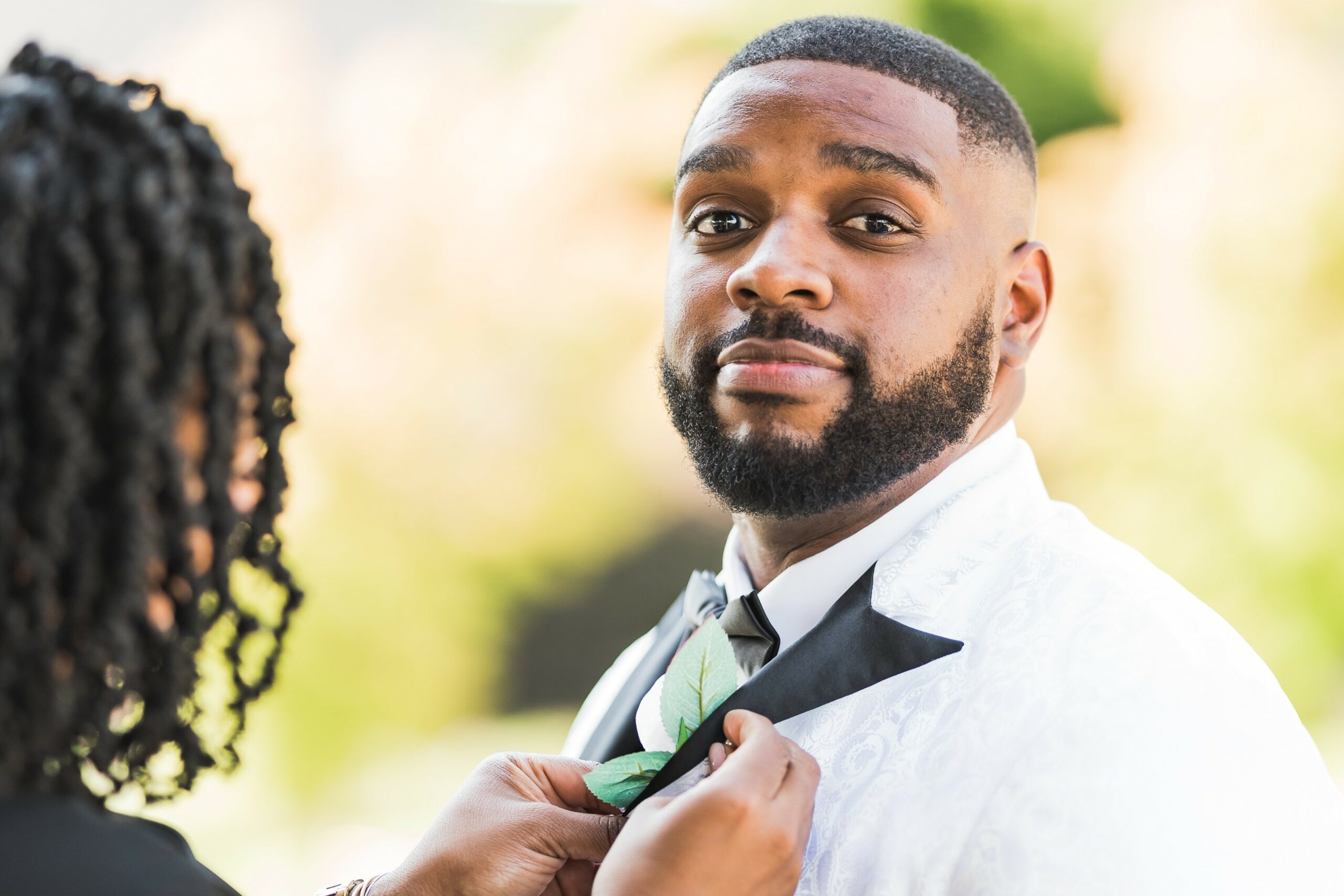 Wedding reality TV shows & movies with a groom's wedding attire a white tuxedo jacket with black tie.