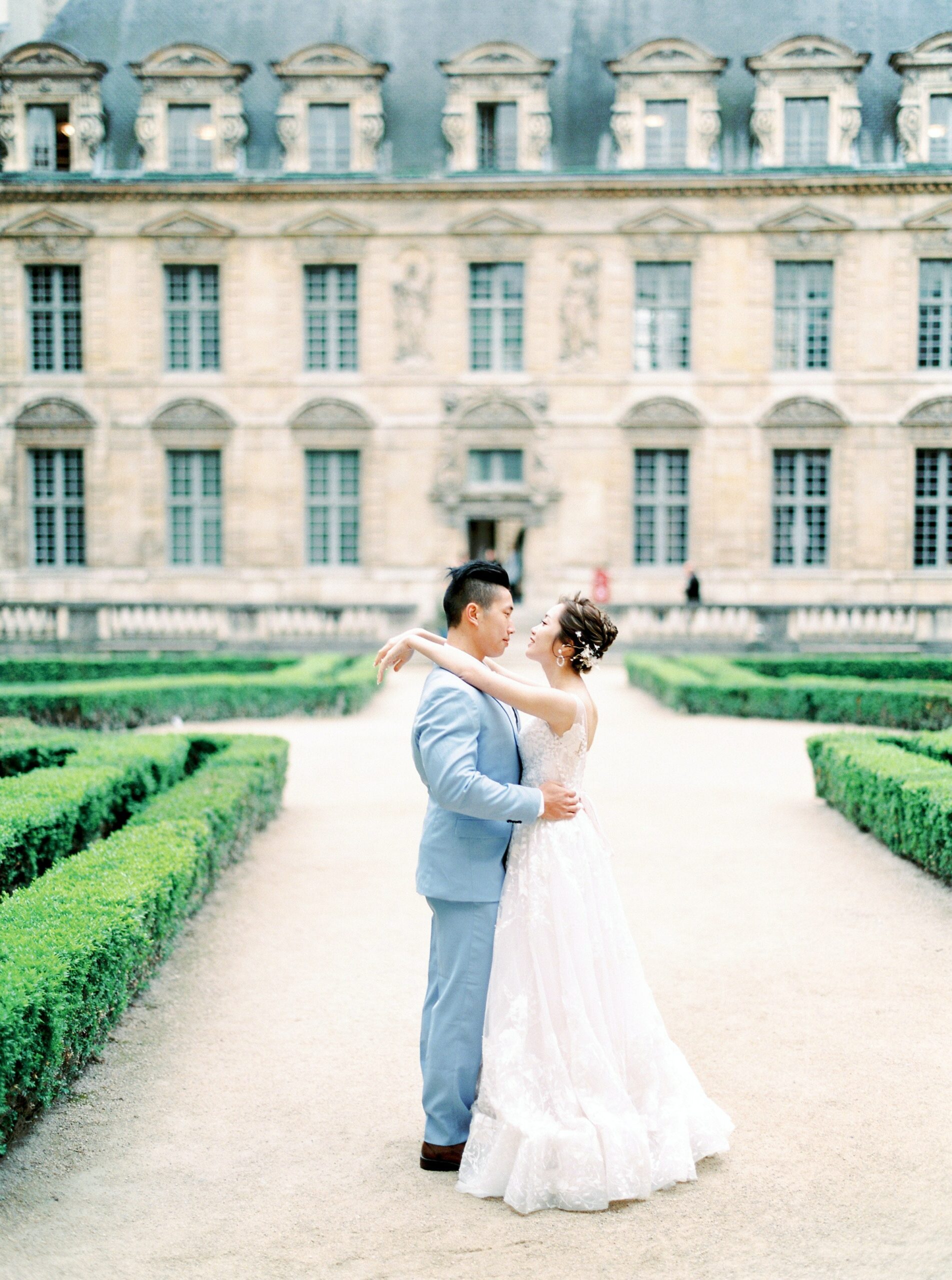 Luxurious wedding venue with the bride and groom embraced in each other's arms during a formal garden wedding.
