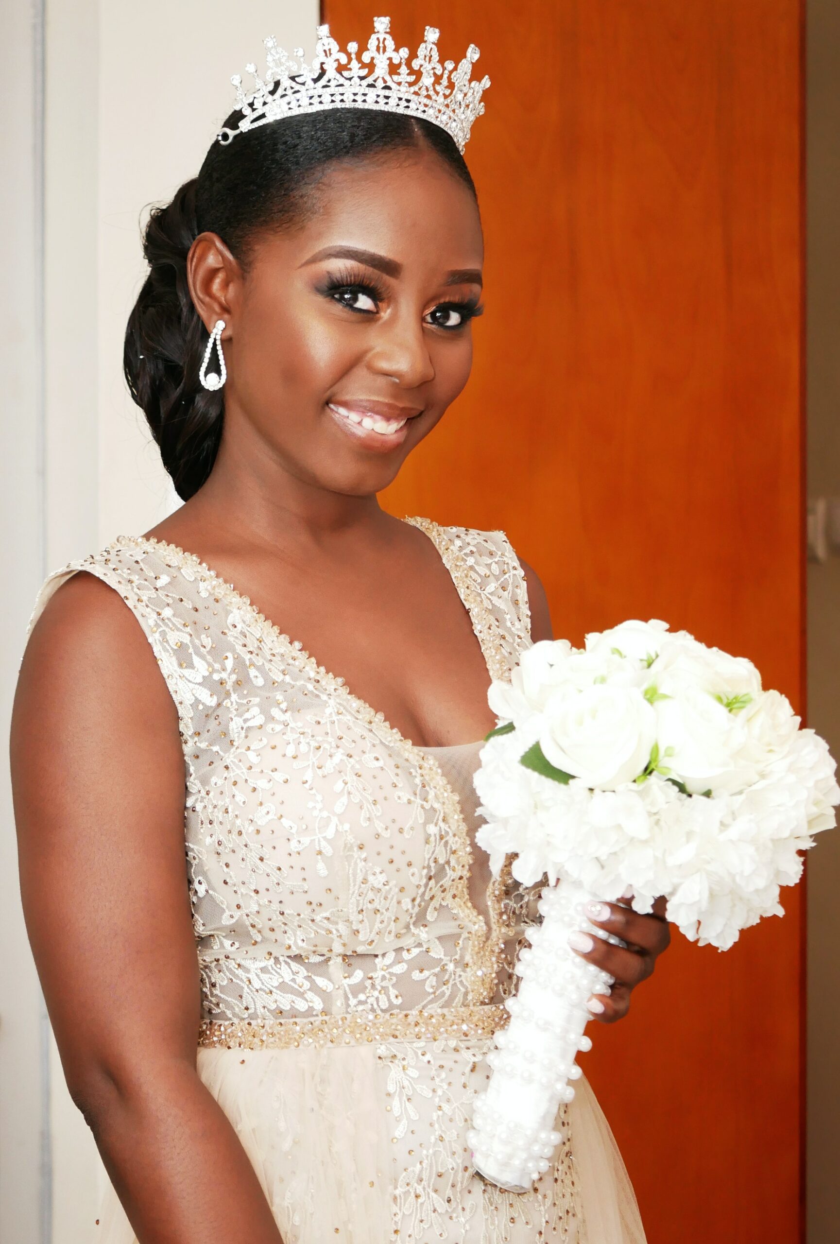 Afro Wedding Hairstyles woman in sleeveless white dress with bouquet of roses