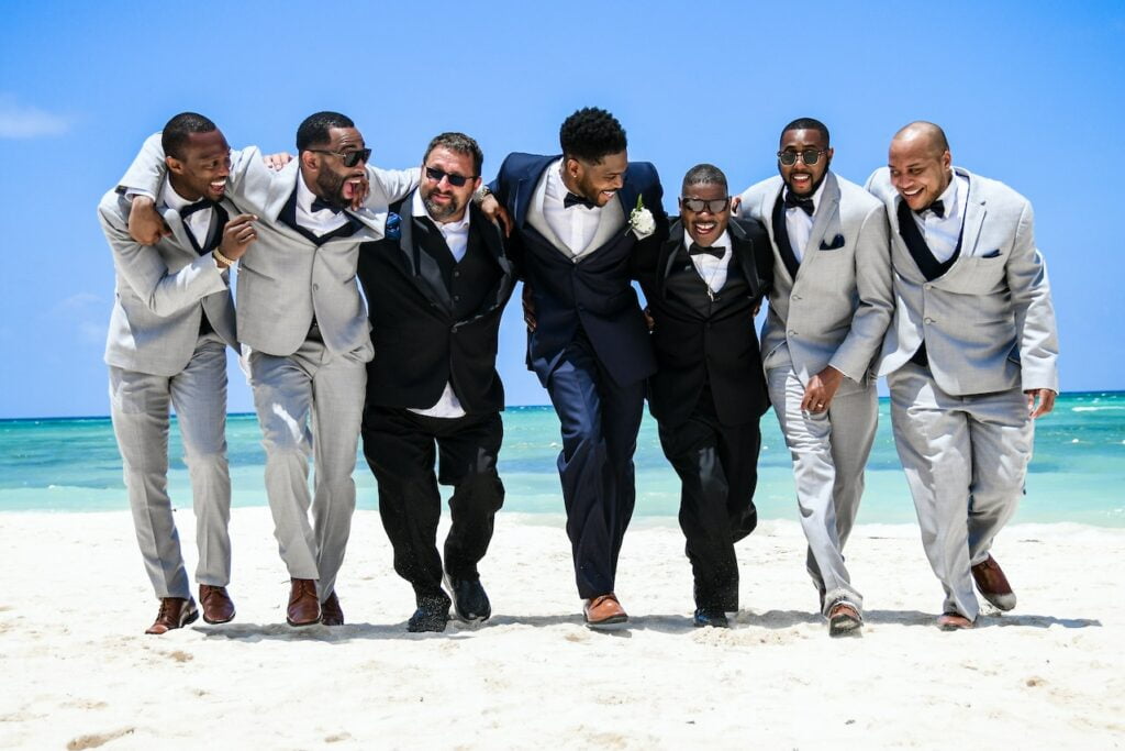 Bruidspersoneel group-of-men-in-black-suits-standing-on-white-sand