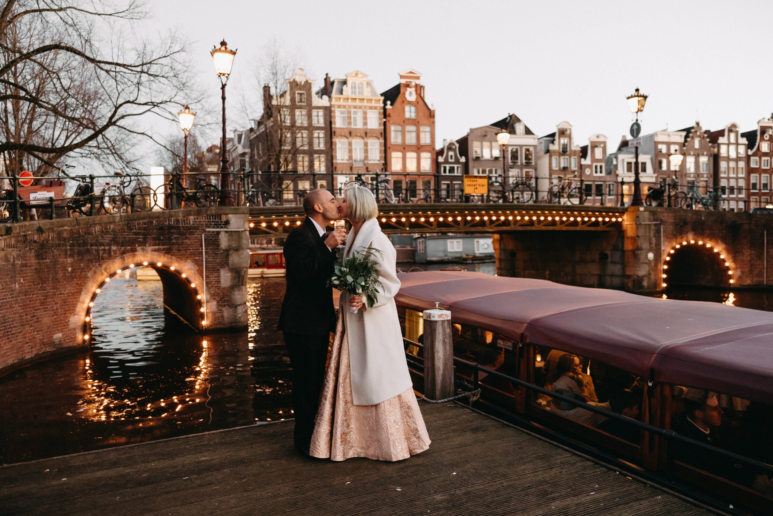  getting married aboard a boat rentaboat amsterdam, evening boat cruise with wedding couple kissing after disembarking.