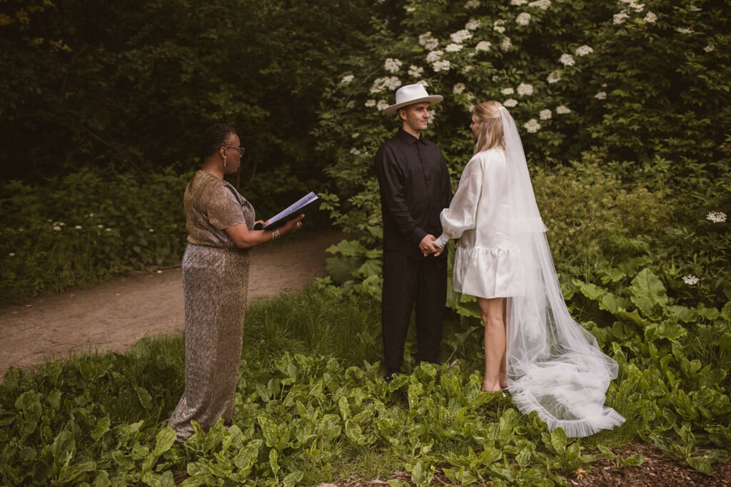 A black wedding officiant being asked 'Can you marry us?' by a bride and groom during a wedding shoot in Vondelpark, Amsterdam 