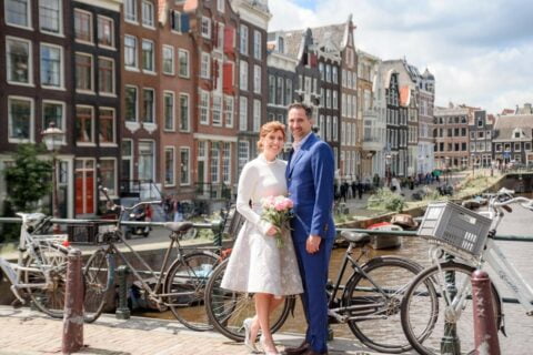 destination wedding planning in Amsterdam, newlyweds standing on canal. ©Victoria Menting