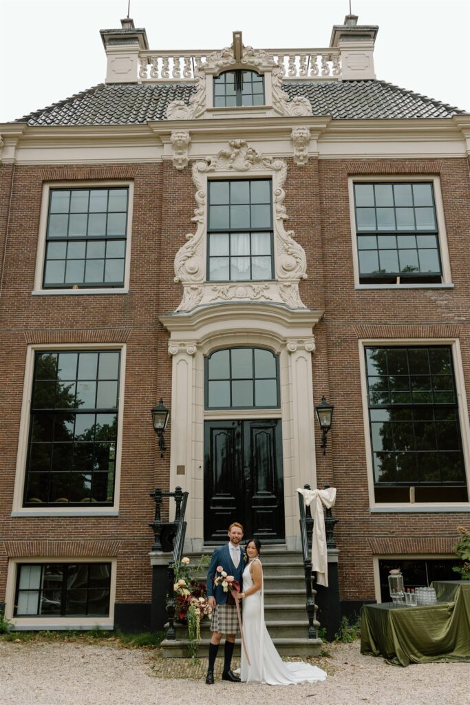 Woman, man and officiant standing outside Dutch castle wedding venue and manor house Huize Frankendael in Amsterdam, the Netherlands